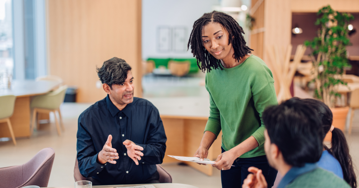 A woman speaking with colleagues about being a resilient leadership.