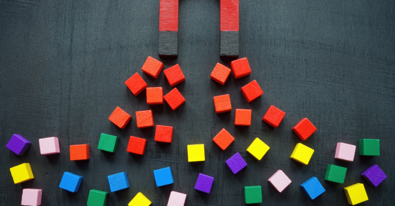 Two magnets attracting red blocks, with other colourful blocks nearby. Symbolises how effective leadership development for retention pulls talent closer.