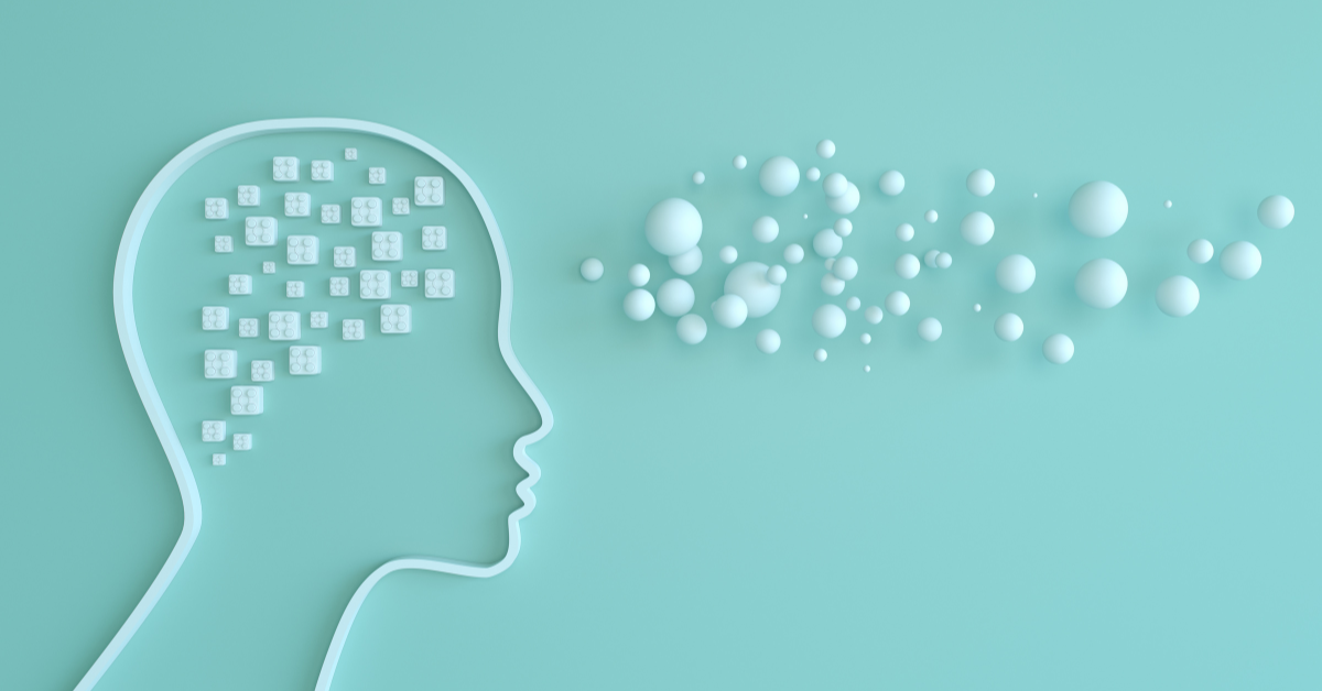 A profile outline of a human head on a mint green background, with many small white cubes inside the head representing thoughts or data, and a cloud of white spheres floating outwards from the forehead, symbolizing ideas or communication. This image relates to emotional intelligence.