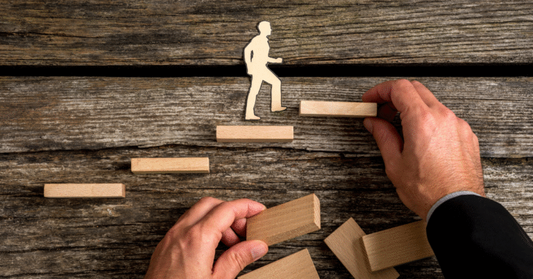 An image of a person walking up stairs that someone else is placing in front of them representing how to ask for a promotion