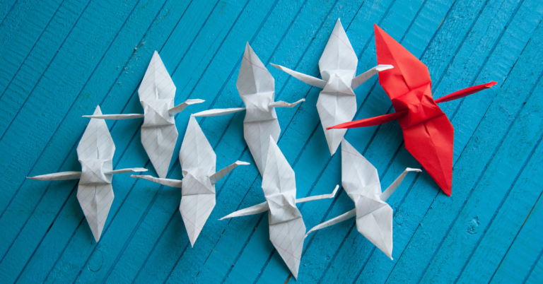 Paper cranes with one red and the rest white representing expert to executive.