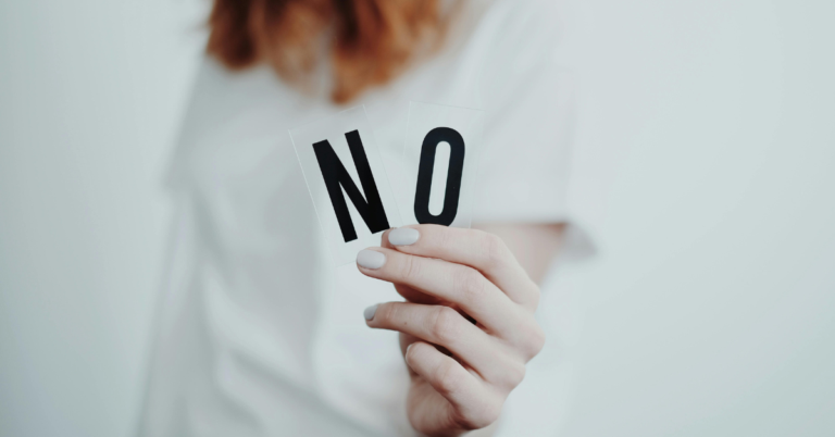A lady holding up the letters 'N' 'O' to spell 'no', representing setting boundaries